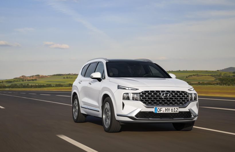 White Hyundai Santa Fe driving front and right side